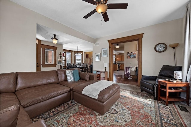 living room with wood finished floors, visible vents, and a ceiling fan