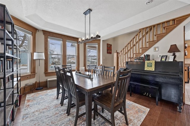 dining space featuring baseboards, hardwood / wood-style floors, stairs, a textured ceiling, and a chandelier