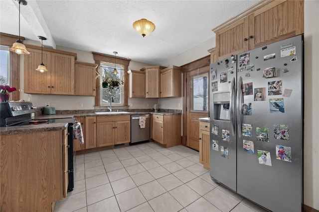 kitchen with hanging light fixtures, a textured ceiling, appliances with stainless steel finishes, and a sink