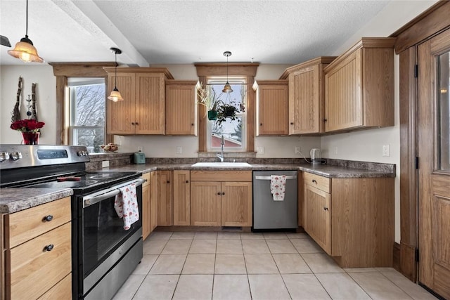 kitchen featuring a textured ceiling, appliances with stainless steel finishes, a sink, and pendant lighting