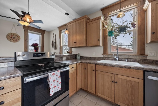 kitchen featuring light tile patterned floors, stainless steel appliances, a sink, dark countertops, and decorative light fixtures