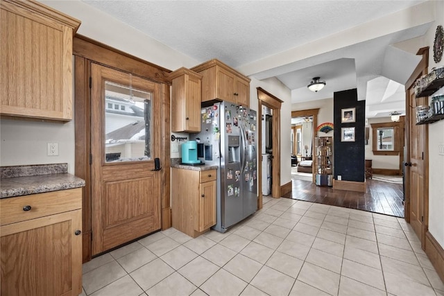 kitchen featuring light tile patterned floors, baseboards, a textured ceiling, and stainless steel fridge with ice dispenser