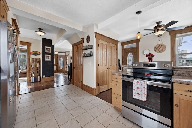 kitchen featuring light tile patterned floors, appliances with stainless steel finishes, a textured ceiling, and beamed ceiling