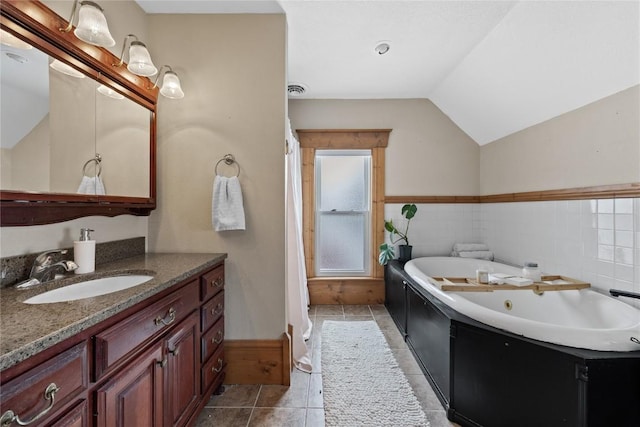 full bath featuring tile patterned flooring, vanity, tile walls, vaulted ceiling, and a tub with jets