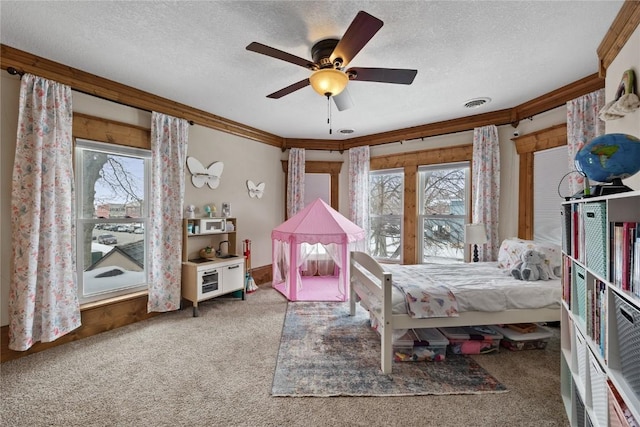 carpeted bedroom featuring visible vents, crown molding, a textured ceiling, and ceiling fan