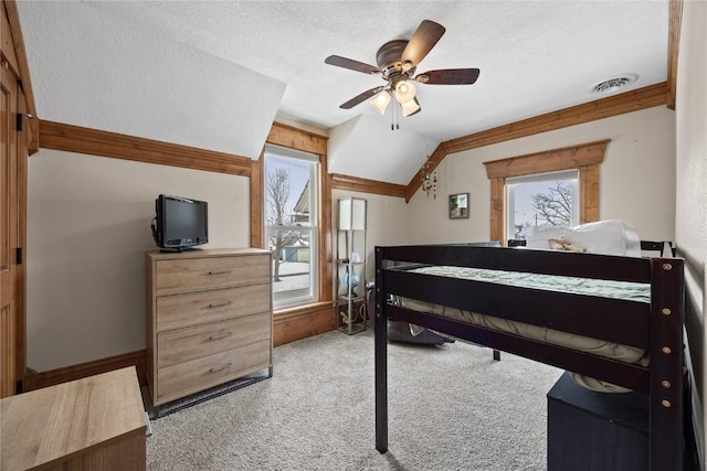 bedroom with visible vents, light colored carpet, ceiling fan, vaulted ceiling, and a textured ceiling