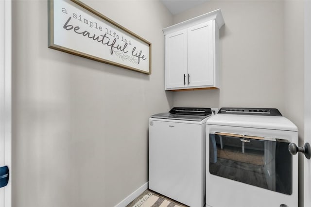 washroom featuring cabinet space, baseboards, and separate washer and dryer