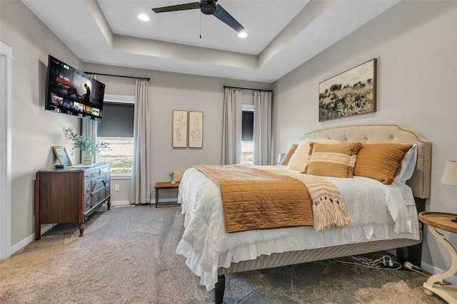 carpeted bedroom with a tray ceiling, ceiling fan, baseboards, and recessed lighting