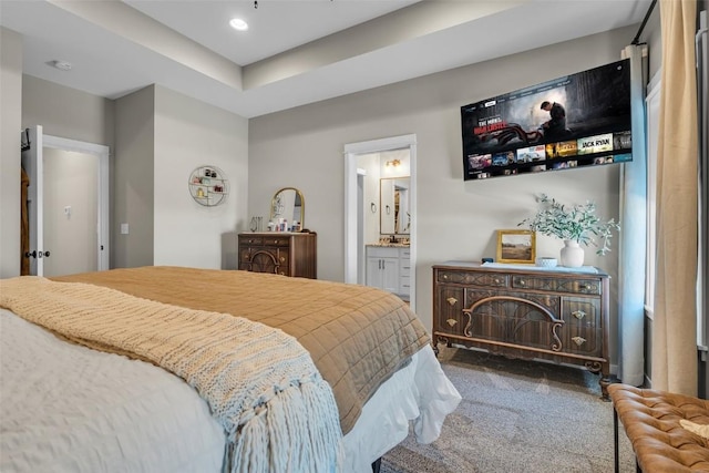 carpeted bedroom with ensuite bath and recessed lighting