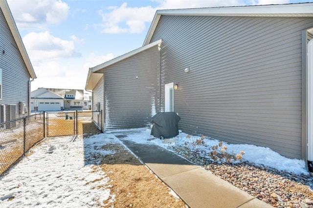 view of snow covered exterior with an outbuilding and fence