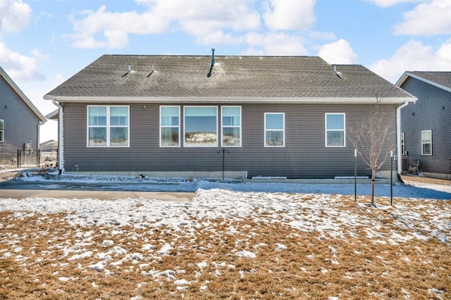 snow covered back of property featuring roof with shingles