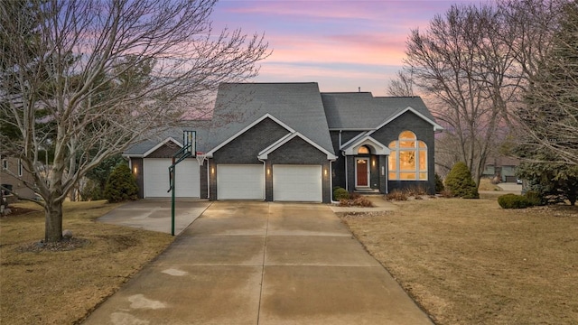 view of front of property with an attached garage, a front lawn, concrete driveway, and brick siding