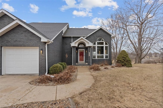 view of front of house featuring a garage, driveway, brick siding, and roof with shingles