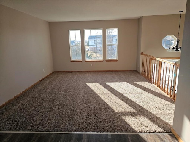 carpeted spare room featuring baseboards and a chandelier