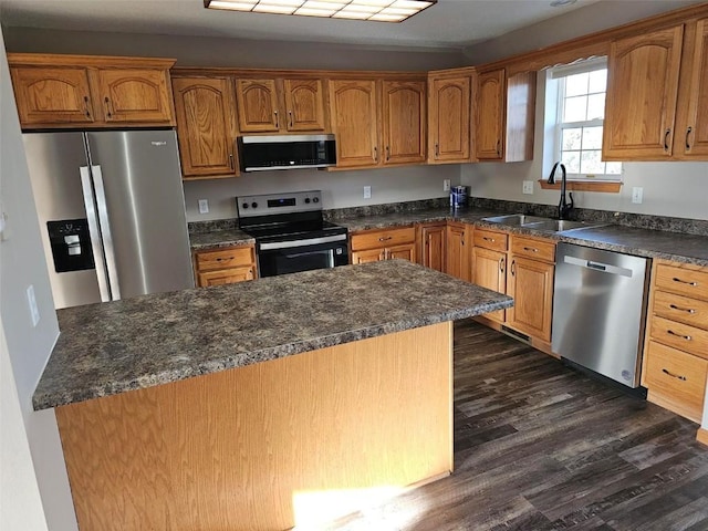 kitchen with stainless steel appliances, brown cabinetry, dark wood-type flooring, and a sink