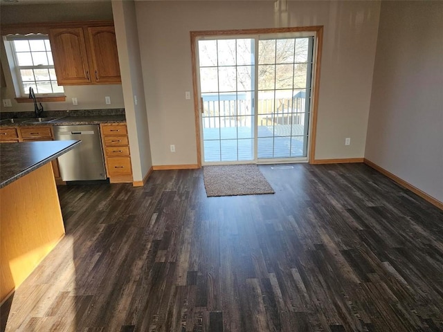 203 Maxwell Dr, Shellsburg, IA 52332 - kitchen with stainless steel dishwasher, dark wood-type flooring, a sink, dark countertops, and baseboards