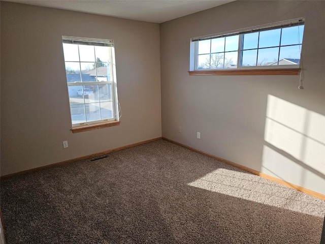 carpeted spare room featuring visible vents and baseboards