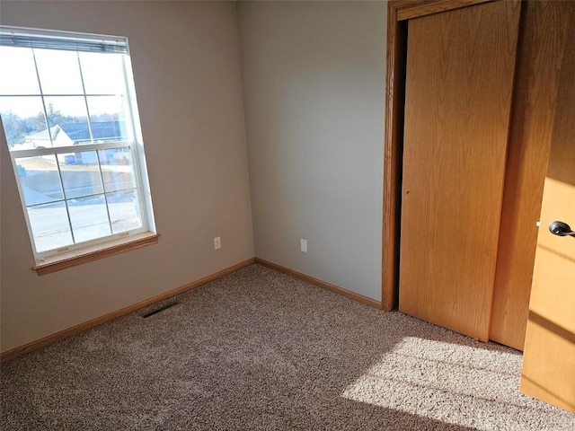 unfurnished bedroom with a closet, carpet flooring, visible vents, and baseboards