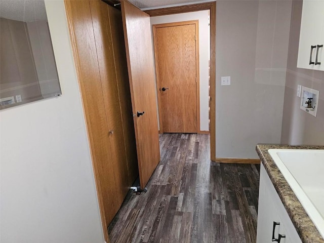 corridor with dark wood-style floors, baseboards, and a sink