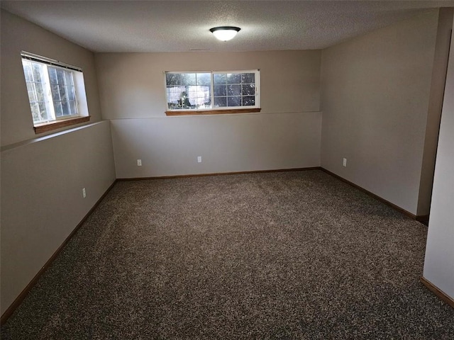 carpeted empty room with a textured ceiling and baseboards