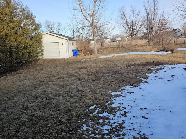 yard covered in snow with a garage and an outdoor structure