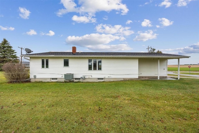 rear view of house featuring central AC unit, a lawn, and a chimney