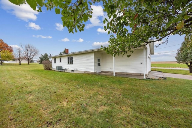 back of house featuring a patio area, a yard, a chimney, and central AC unit