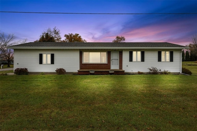 single story home featuring brick siding and a lawn