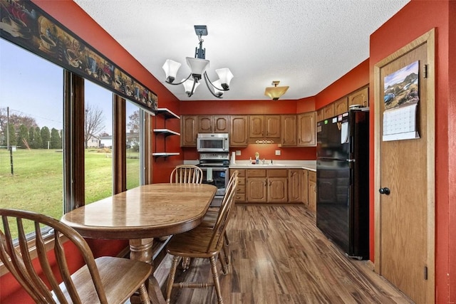 kitchen with dark wood-style floors, stainless steel appliances, light countertops, an inviting chandelier, and a textured ceiling