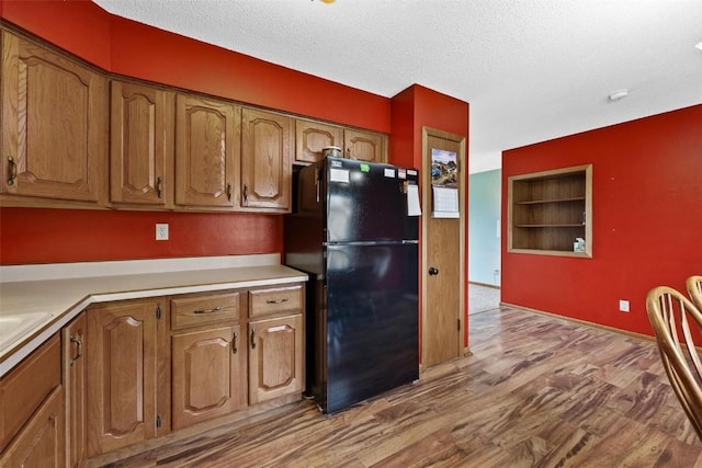 kitchen featuring a textured ceiling, light countertops, wood finished floors, and freestanding refrigerator