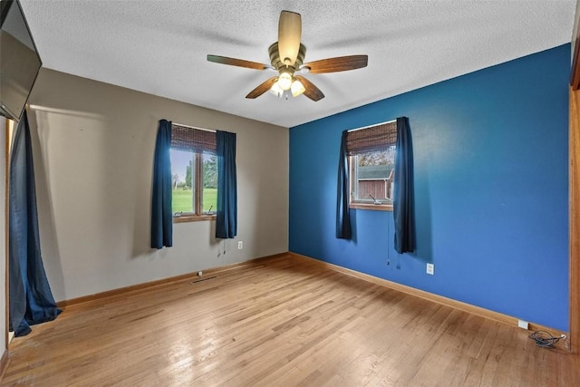 spare room featuring wood finished floors, a ceiling fan, and a healthy amount of sunlight