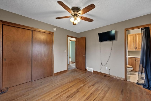 unfurnished bedroom featuring light wood-type flooring, a closet, visible vents, and a textured ceiling