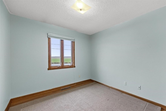 unfurnished room featuring carpet, baseboards, visible vents, and a textured ceiling