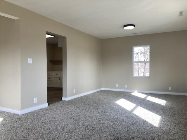 unfurnished room featuring carpet floors, visible vents, and baseboards