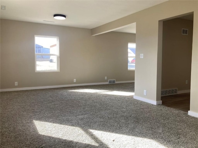 empty room with carpet floors, visible vents, and baseboards