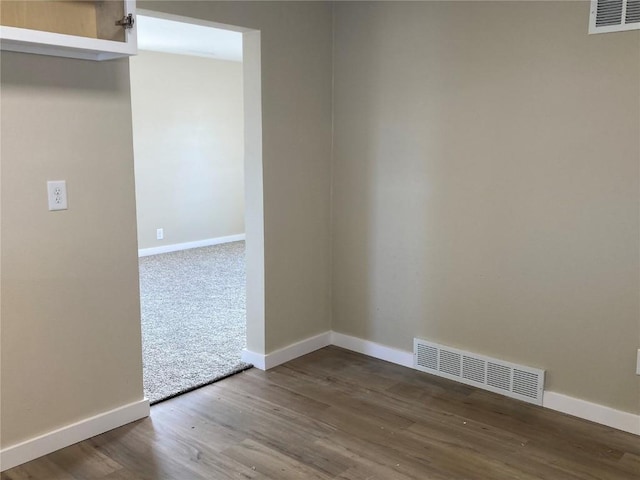 spare room featuring baseboards, visible vents, and wood finished floors