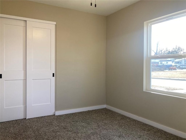 unfurnished bedroom with carpet floors, a closet, and baseboards