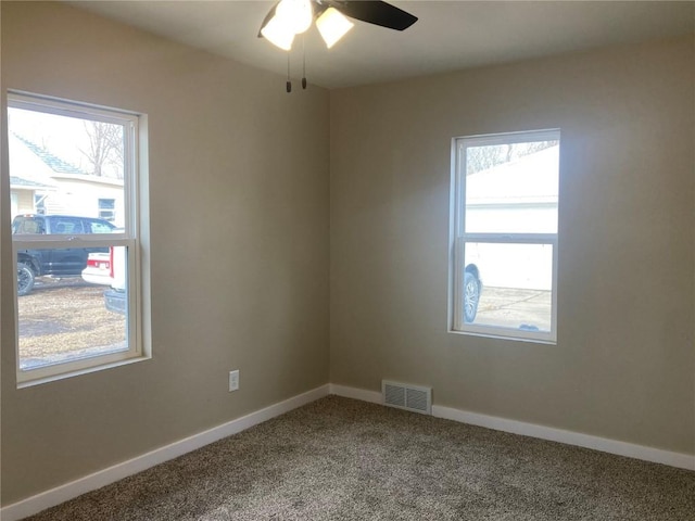 empty room with a wealth of natural light, carpet, visible vents, and baseboards