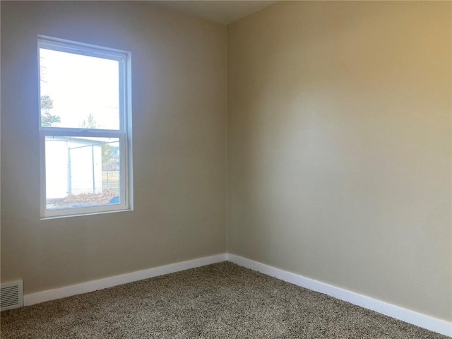 carpeted spare room with visible vents and baseboards