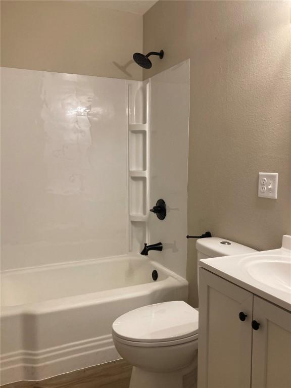 bathroom featuring toilet, bathtub / shower combination, wood finished floors, and vanity