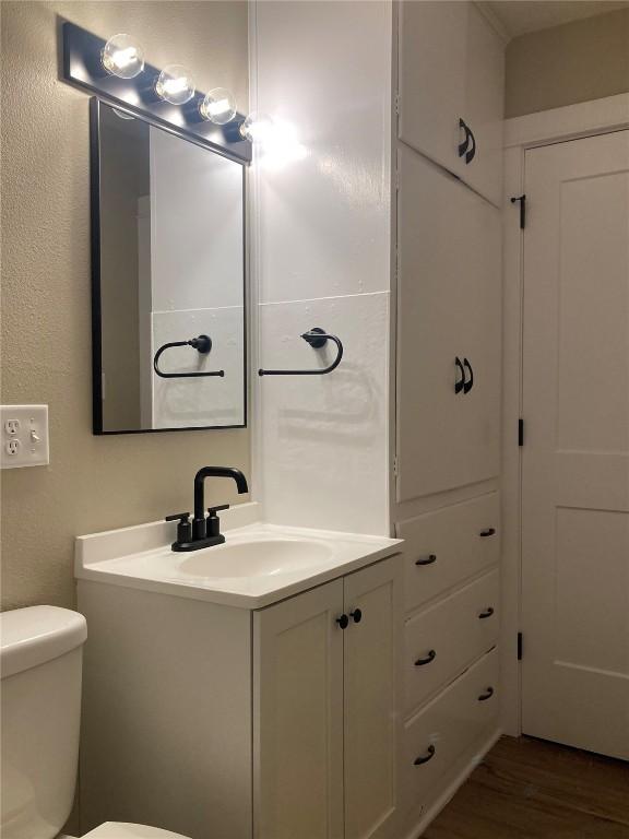 bathroom featuring toilet, wood finished floors, and vanity