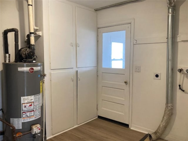 doorway to outside with gas water heater and wood finished floors