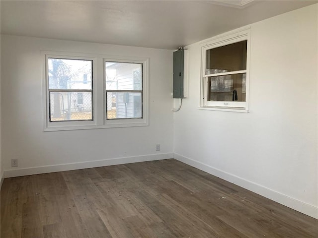 spare room featuring dark wood-style flooring, electric panel, and baseboards