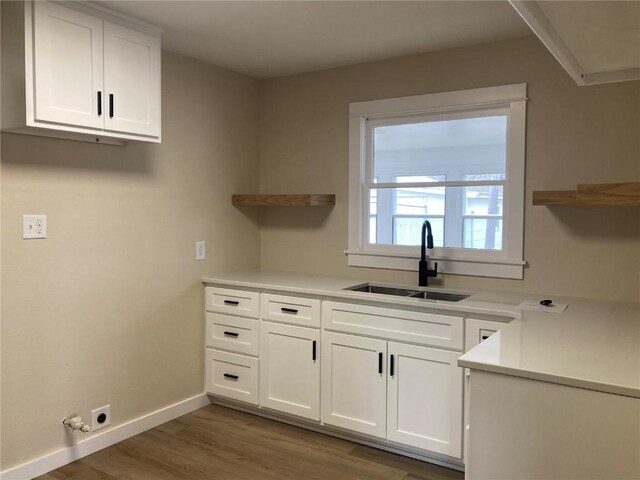 208 G Ave, Vinton, IA 52349 - kitchen featuring open shelves, a sink, white cabinets, wood finished floors, and baseboards