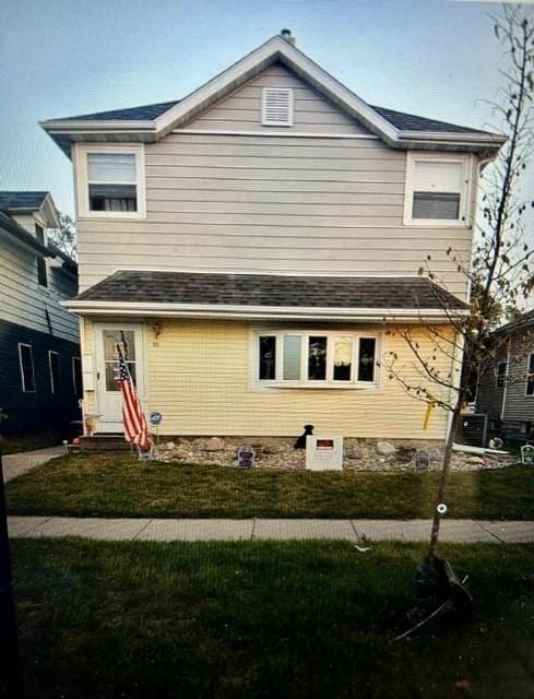 view of front facade featuring a front lawn and a shingled roof