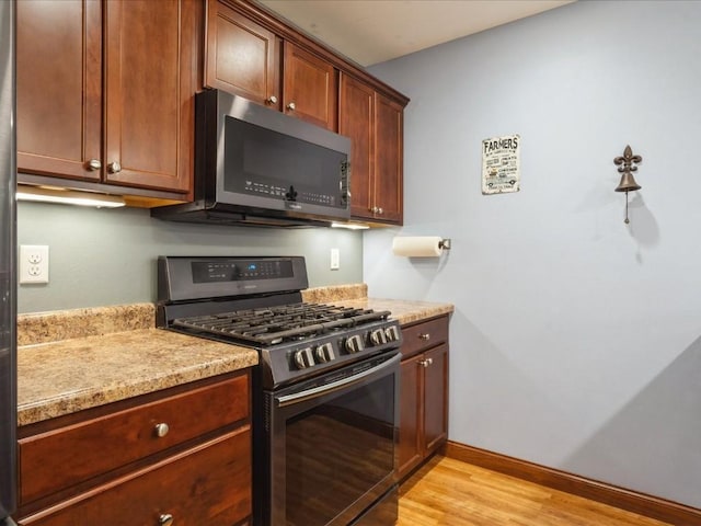 kitchen featuring light wood-style flooring, baseboards, and stainless steel appliances