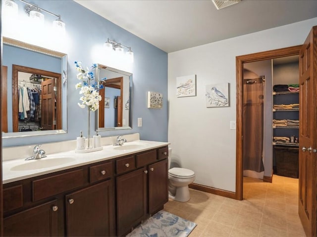 bathroom featuring a sink, toilet, a spacious closet, and double vanity