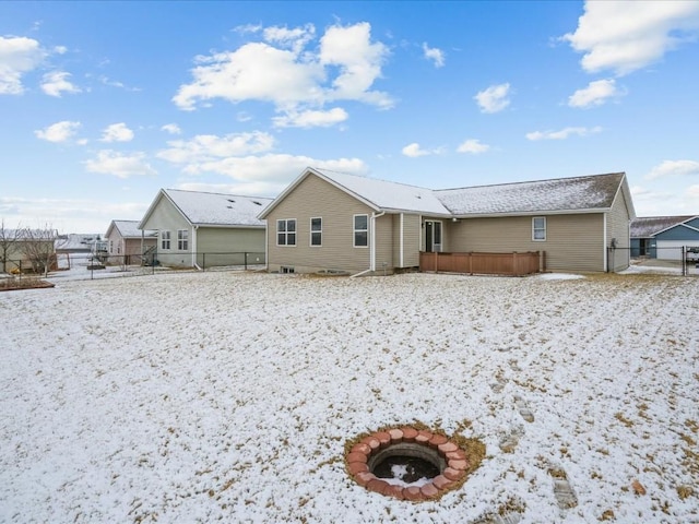 snow covered back of property with fence and a wooden deck