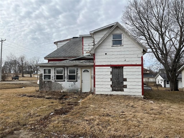 rear view of property featuring a shingled roof