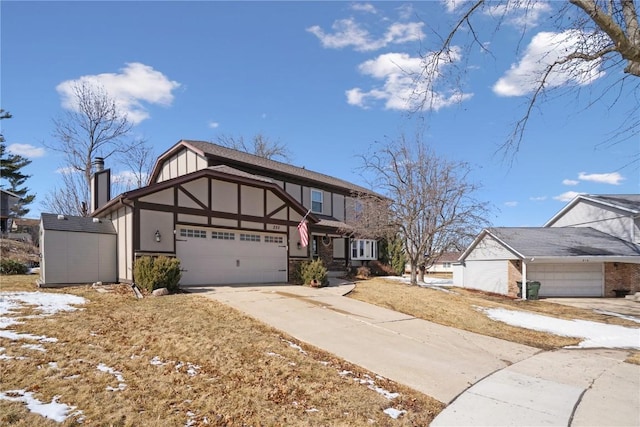 english style home with a garage, driveway, a chimney, and stucco siding